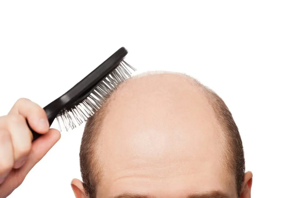 Man brushing his balding head.